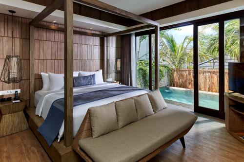 a bedroom with a bed and a couch and a tv at Cross Bali Breakers in Jimbaran