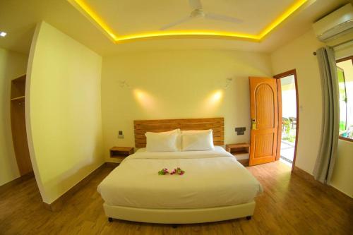 a bedroom with a large white bed with flowers on it at Tiger Shark Residence & Dive in Fuvahmulah