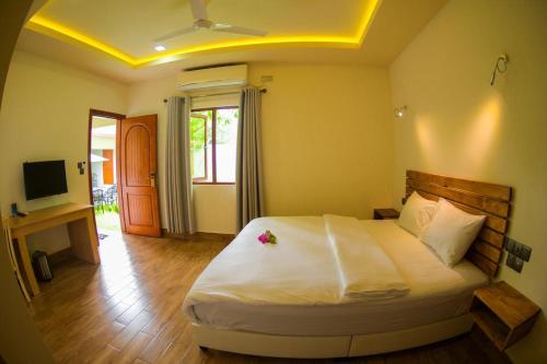 a bedroom with a large bed and a television at Tiger Shark Residence & Dive in Fuvahmulah