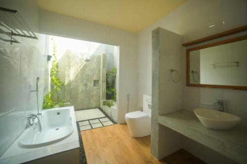 a bathroom with a tub and a sink and a toilet at Tiger Shark Residence & Dive in Fuvahmulah