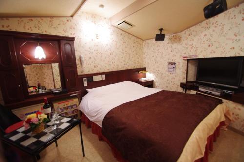 a hotel room with a bed and a flat screen tv at Alohain Yonago in Yonago