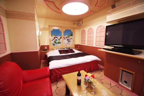 a hotel room with a bed and a flat screen tv at Alohain Yonago in Yonago