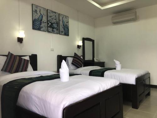a room with three beds with white sheets at Jasmine Vangvieng Hotel in Vang Vieng