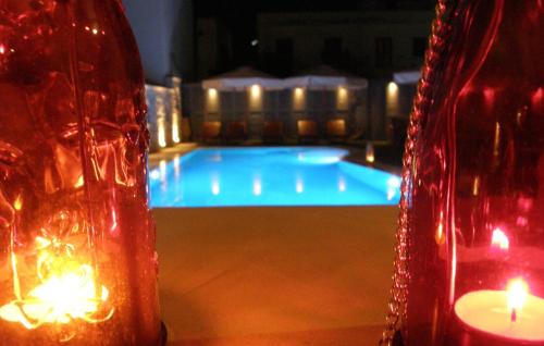 a swimming pool with two candles and a red vase at Anna Platanou Hotel in Parikia