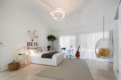 een witte slaapkamer met een bed en een schommel bij La Boheme Whitsunday in Airlie Beach
