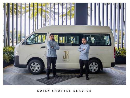 two men standing in front of a van at Jinhold Hotel & Serviced Apartment in Miri