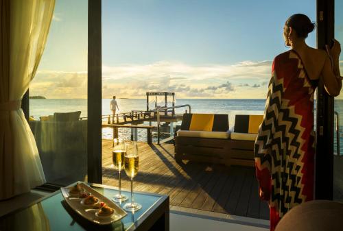 a woman standing on a deck looking out at the ocean at Angsana Velavaru in Dhaalu Atoll
