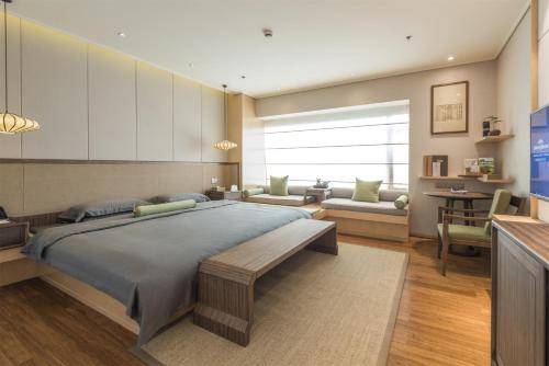 a bedroom with a large bed and a living room at Howard Johnson Conference Resort Chengdu in Dujiangyan