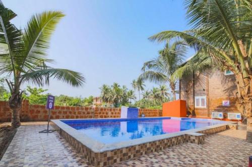una piscina en un patio con palmeras en Casa Seaesta Beach Cottages and Suites, en Arambol