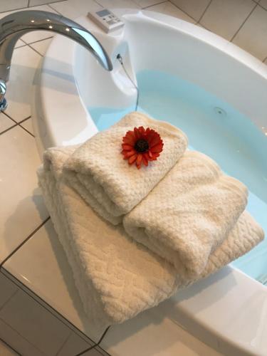 a towel with a red flower sitting on a bath tub at シーブリーズ古宇利 in Nakijin