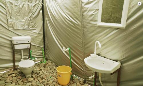a bathroom with a toilet and a sink in a tent at Bhaga Eco Camp in Jispa