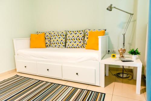 a white bed with orange pillows and a side table at Aegean Studio by the Sea in Perea