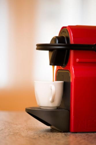 a coffee maker is pouring coffee into a cup at City Appartements Villach in Villach