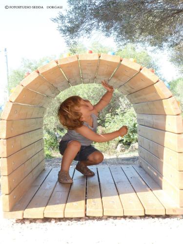 a young child playing in a wooden play structure at Country House S'Ozzastru in Dorgali