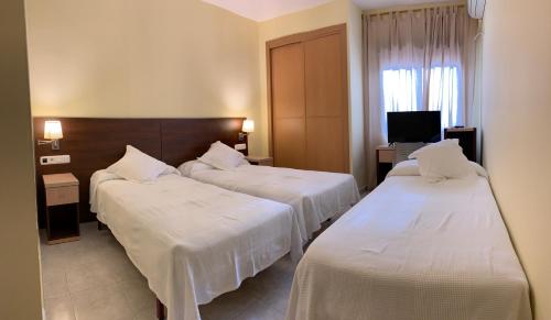 a hotel room with three beds and a television at Hostal Monasterio de Rueda in Sástago