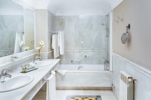 a white bathroom with two sinks and a bath tub at Parador de Mérida in Merida