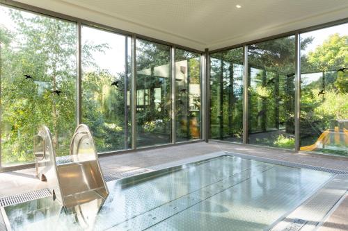 an indoor swimming pool in a house with windows at Hotel Bemelmans-Post in Collalbo