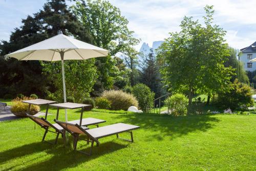 two picnic tables and an umbrella in the grass at Hotel Bemelmans-Post in Collalbo