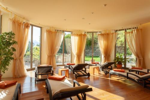 a living room with chairs and tables and windows at Hotel Bemelmans-Post in Collalbo