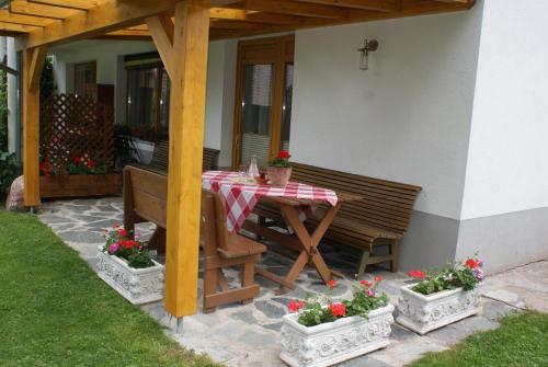 a wooden table and bench on a patio with flowers at Appartements Fritz Sagmeister in Jenig
