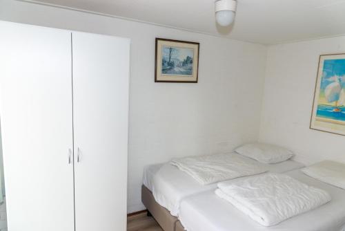 een witte slaapkamer met een bed en een kast bij Hello Zeeland - Vakantiehuis Duinroos 167 in Breskens