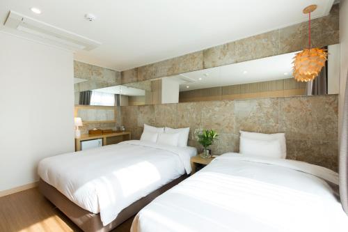 two beds in a hotel room with white sheets at Hotel Nafore in Seoul