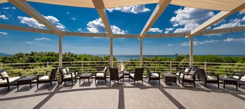 a patio with chairs and tables and a view of the ocean at Tombolo Talasso Resort in Marina di Castagneto Carducci