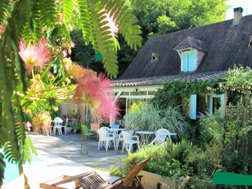 a house with a patio and tables and chairs at Maison d'Hôtes Le Moulin Pointu in Sainte-Nathalène