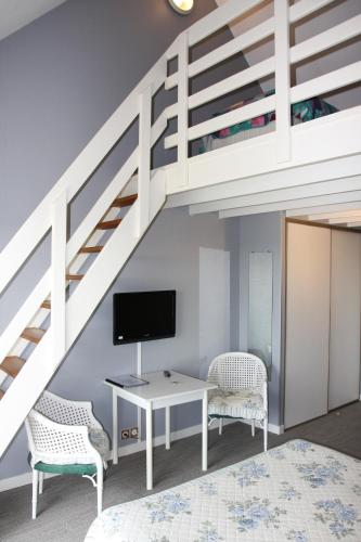 a bedroom with a bunk bed and a desk with a tv at L'Hippocampe in Plouharnel