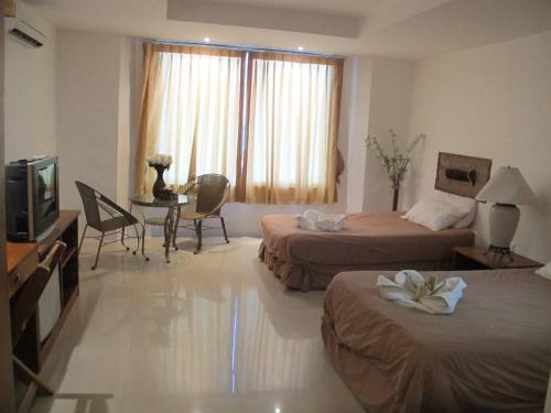 a hotel room with two beds and a television at Jomtien Hostel 3 in Jomtien Beach