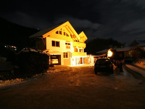 a house with a car parked in front of it at night at Appartements Enzian in Finkenberg