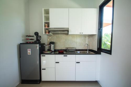 a kitchen with white cabinets and a stainless steel refrigerator at Good Night Pool Villa Phuket - SHA Plus in Phuket Town