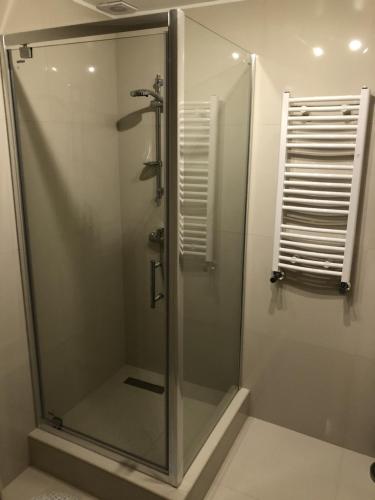 La salle de bains est pourvue d'une douche avec une porte en verre. dans l'établissement Hotel Restauracja Prezydencka, à Legionowo