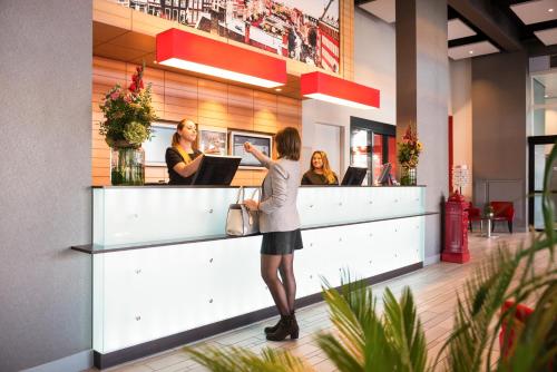 a woman standing in front of a counter in a restaurant at ibis Leiden Centre in Leiden