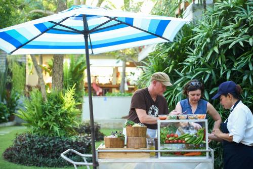 a group of people standing around a food cart with an umbrella at Let's Sea Hua Hin Al Fresco Resort in Hua Hin