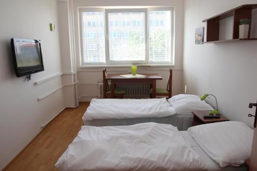 two beds in a room with a tv and a table at City Building in Šaca