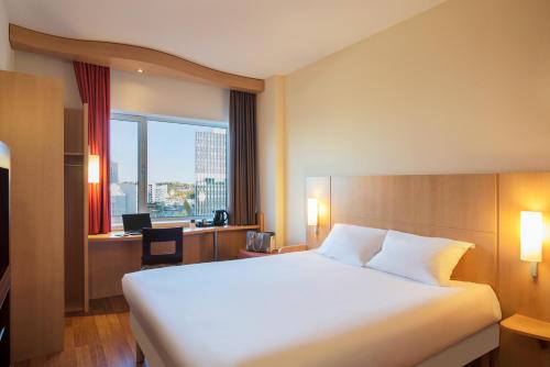 a hotel room with a bed and a desk and a window at ibis Leiden Centre in Leiden