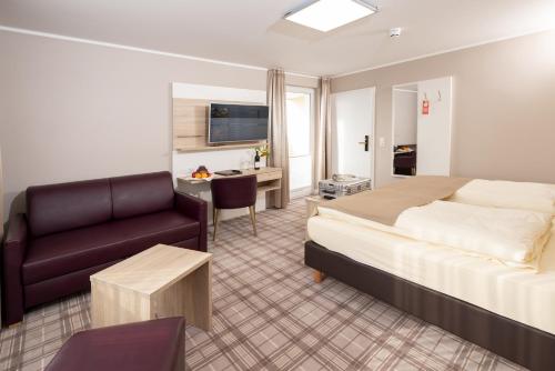 um quarto de hotel com uma cama, um sofá e uma secretária em Hotel Tiek Superior em Meppen