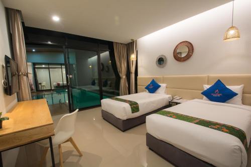 a hotel room with two beds and a table and a desk at Good Night Pool Villa Phuket - SHA Plus in Phuket Town
