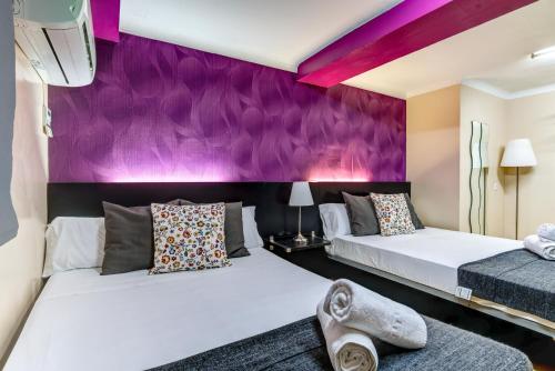 2 camas en una habitación con paredes moradas en Sun & Moon Hostel, en Barcelona