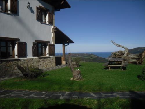 a house with a picnic table and a bench in the grass at Casa Rural Orortegi in Aia