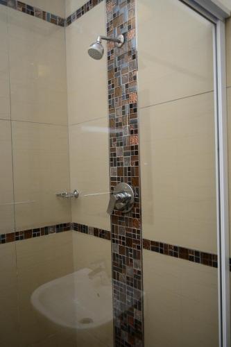 a shower with a glass door and a sink at Tudor House Hotel in Durban