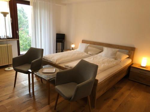 a bedroom with a bed and two chairs and a table at Pension Dabrunz in Heimbach