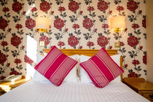 um quarto com uma cama com duas almofadas cor-de-rosa em Ivy Bush Royal Hotel by Compass Hospitality em Carmarthen