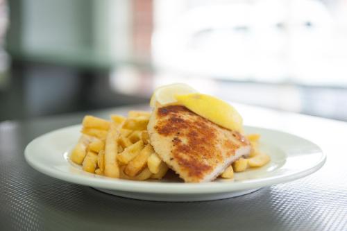 a plate of food with a piece of fish and french fries at Riverina hotel in Holbrook