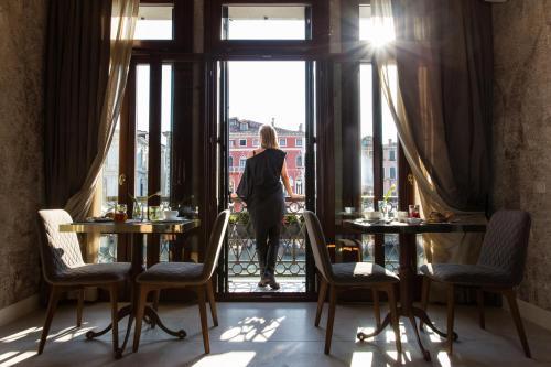 een vrouw die uit het raam van een restaurant kijkt bij Riva del Vin BOUTIQUE HOTEL in Venetië