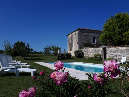 une maison avec piscine et fleurs roses dans l'établissement Les Gîtes de l'Astrée, à Saint-Bris-des-Bois