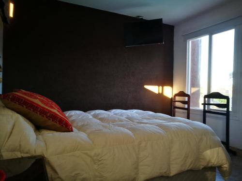 a bedroom with a large white bed with a red pillow at Departamento con parque a metros del mar in Ostende