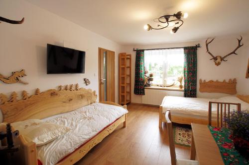 a bedroom with two beds and a tv on the wall at Agroturystyka "u kuremzy" in Bieliny