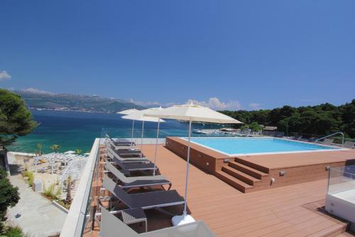 a swimming pool with lounge chairs and an umbrella at Kalamota Beach House in Koločep
